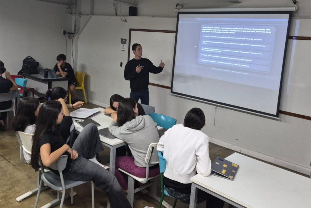 Membro da equipe Aureon apresentando uma questão no projetor para alunos em sala de aula